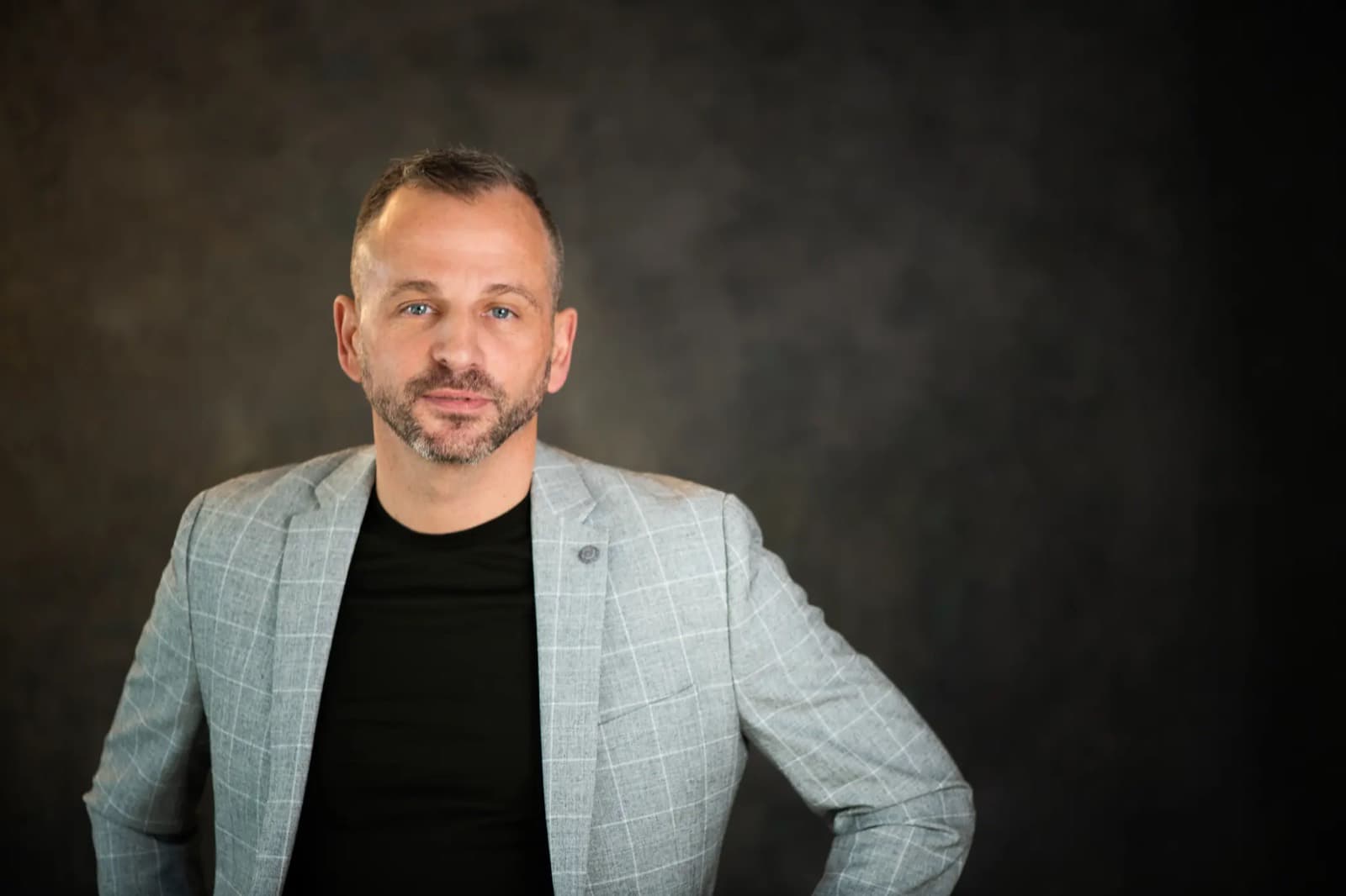 Paul Cohalan in a grey check blazer over a black tee